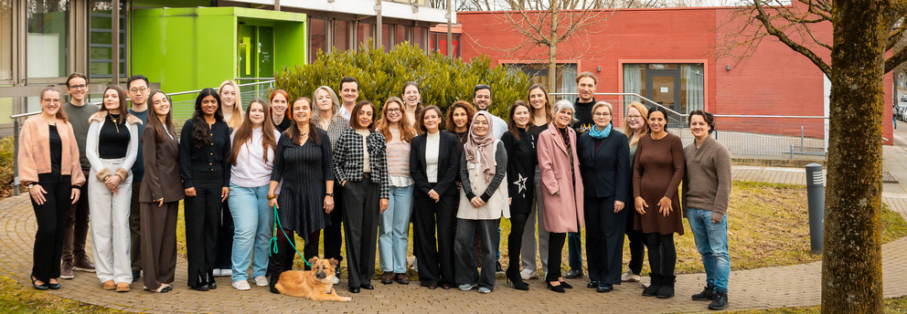 Die Mitglieder des Instituts für Diversitätsstudien (Dezember 2025) laufen über eine Wiese auf dem Campus der TU Dortmund
